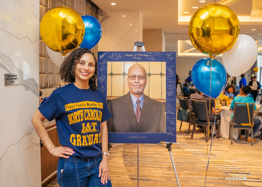 A celebration setup with gold and blue balloons and a framed portrait display.