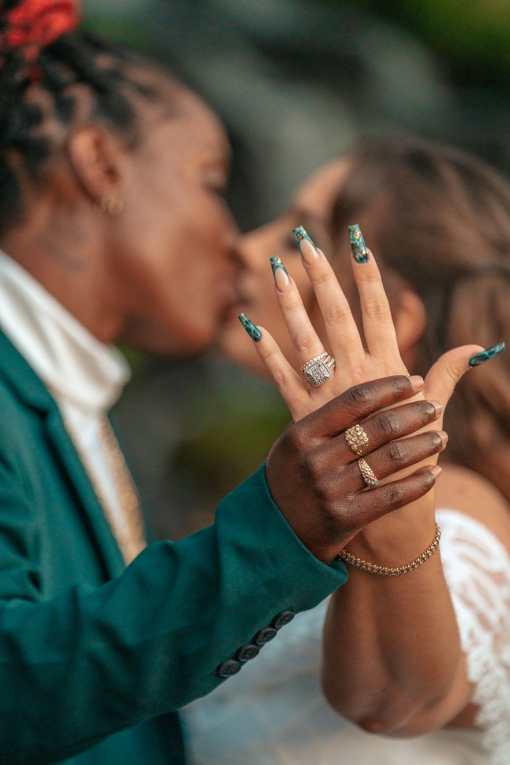 Close-up shot of wedding rings and detailed manicure with hands tenderly embracing.