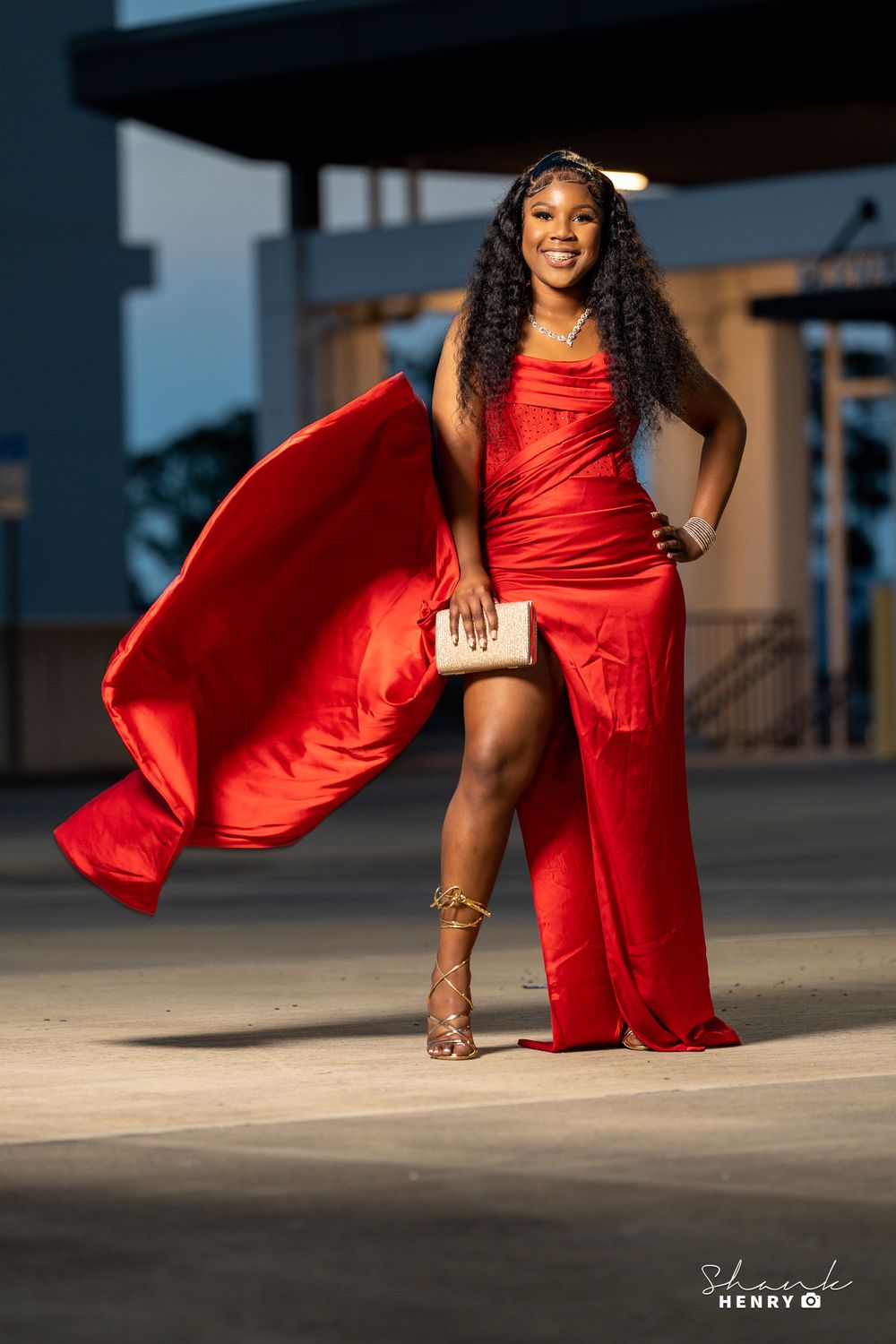Red flowing evening gown creates dramatic movement in outdoor fashion photo.