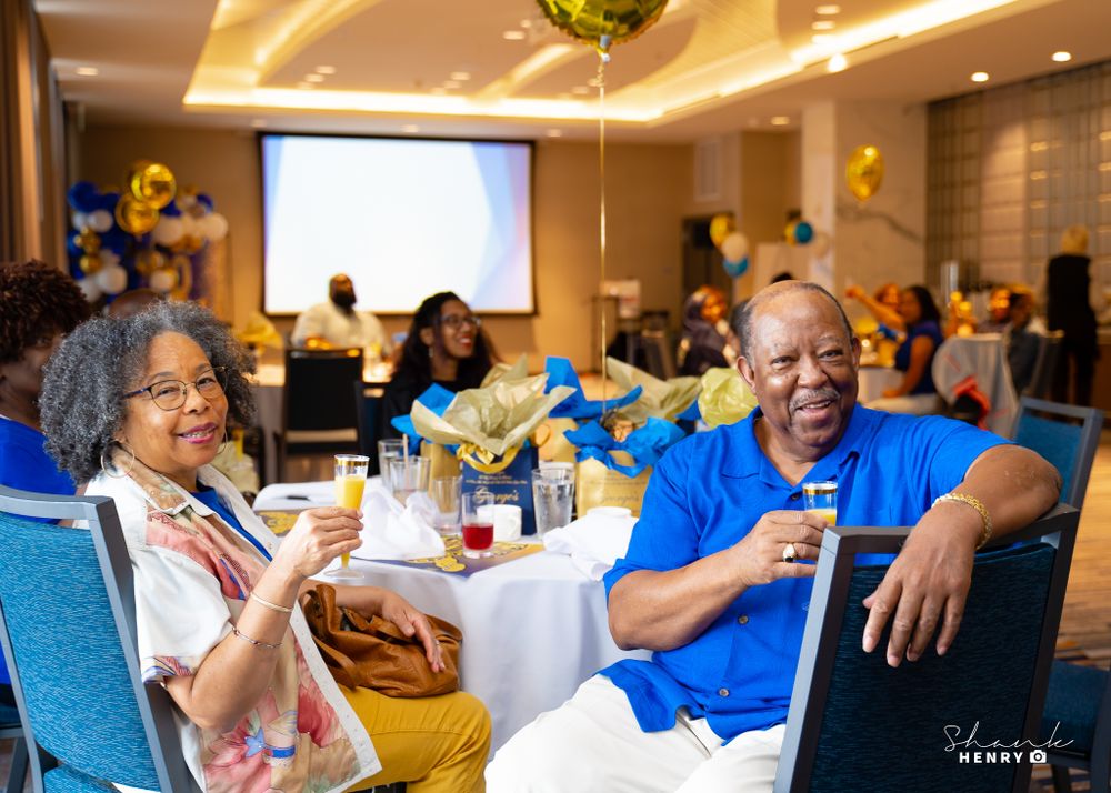 Attendees enjoying refreshments at tables during a formal celebration with gold ceiling lighting.