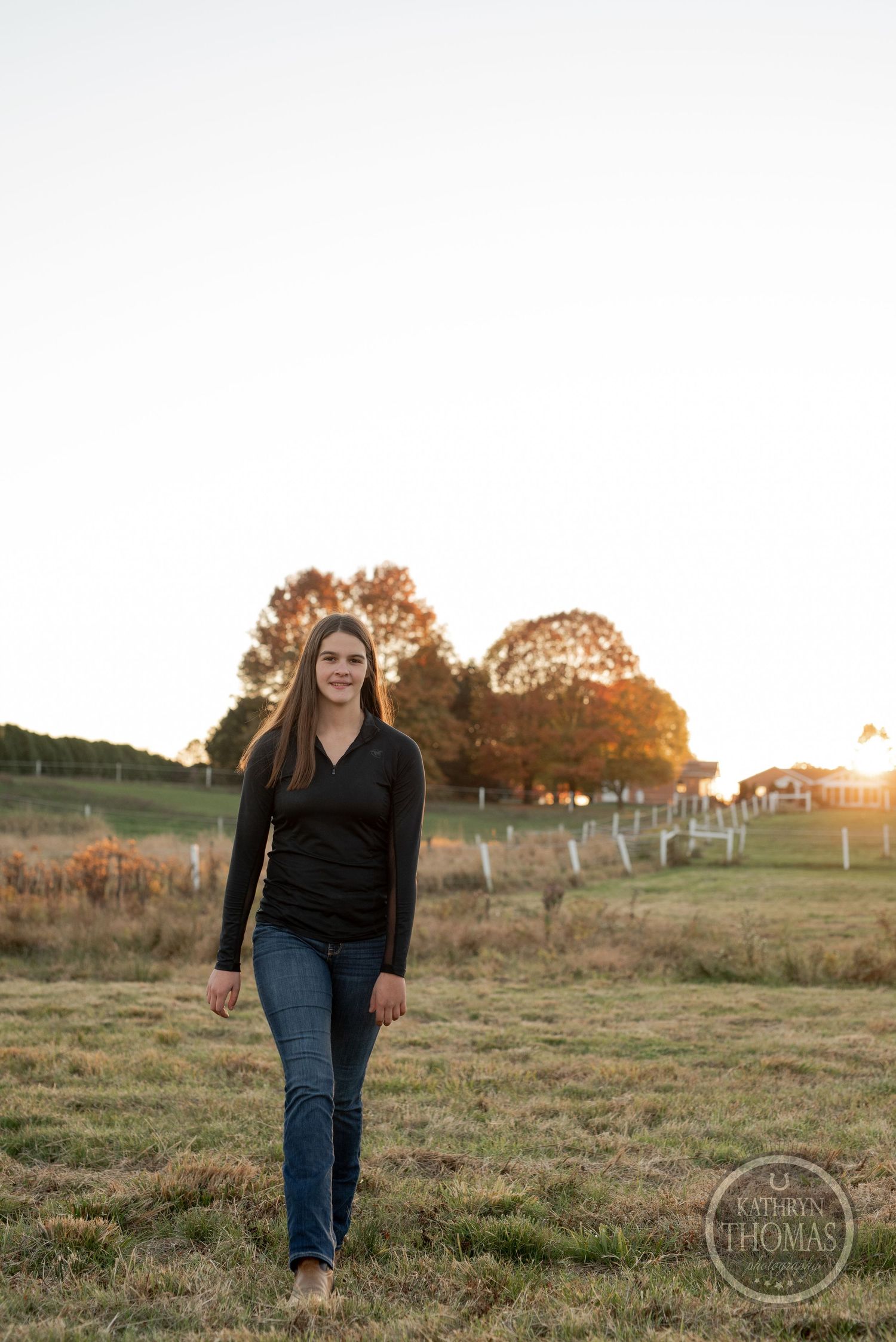 Sunset portrait in open field with warm autumn lighting and fence posts.