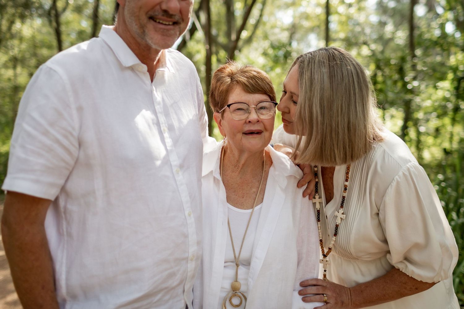 Three people share an intimate moment while laughing together outdoors.