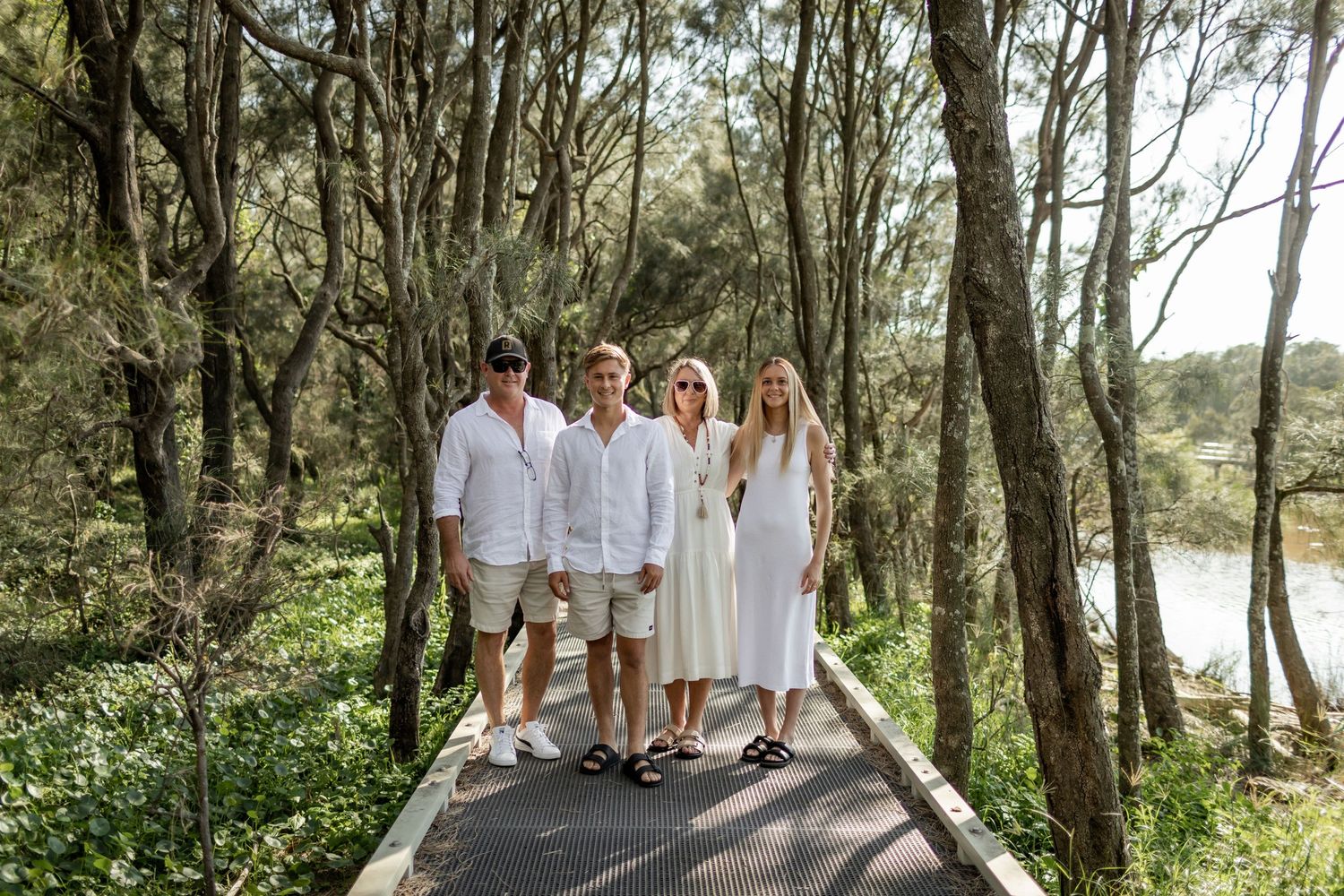 Group walking together on wooden boardwalk through forest setting.
