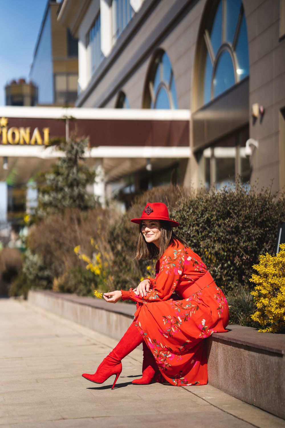 Fashion shoot featuring red traditional Chinese dress and matching hat in urban setting.
