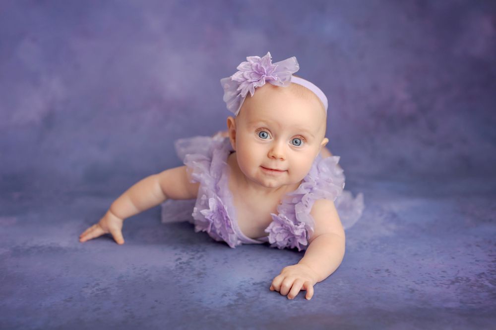 Purple themed portrait with lavender tulle dress against dark backdrop.