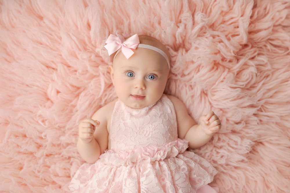 Delicate pink portrait setup with lace dress on fluffy background.