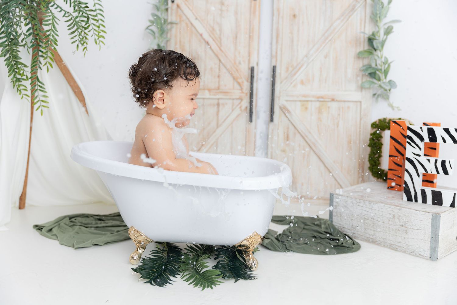 White clawfoot bathtub against rustic barn door backdrop with greenery accents.