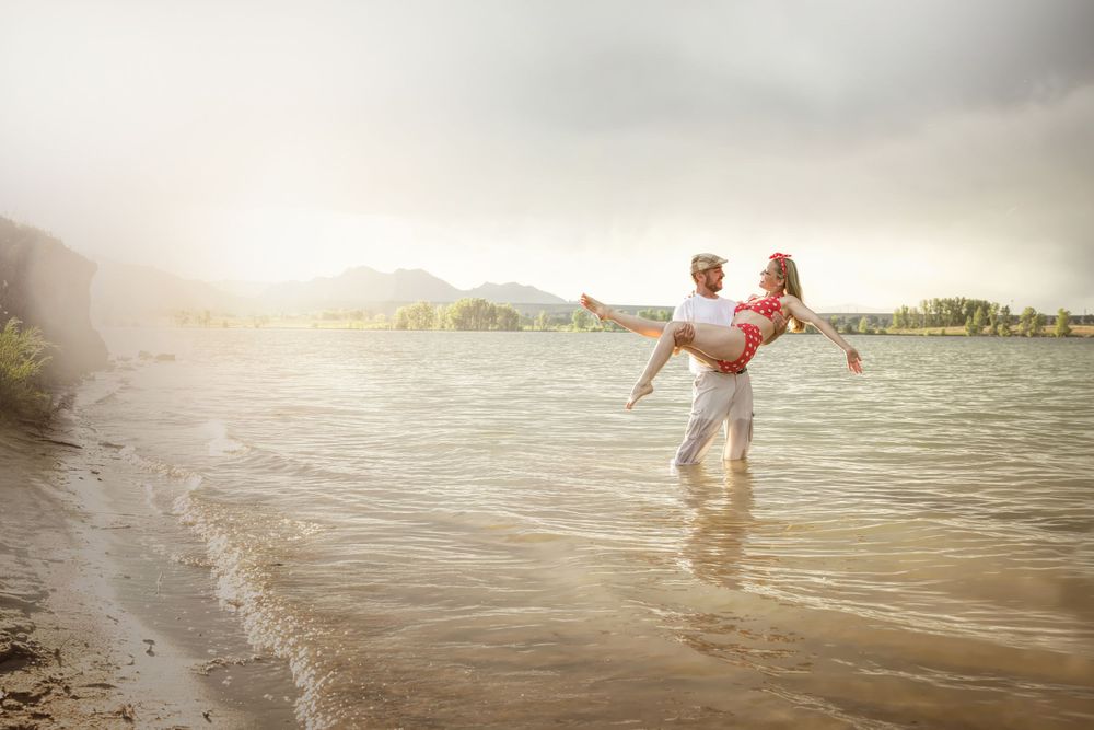Romantic couple embrace in shallow water during golden sunset.