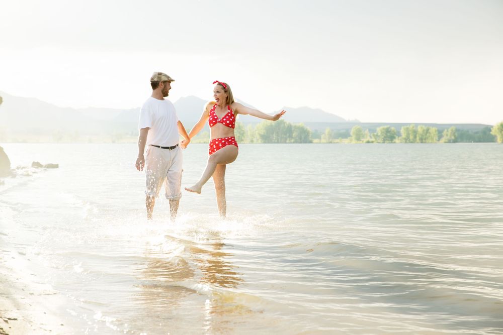 Playful interaction in shallow lake water with mountains and sunlight in background.