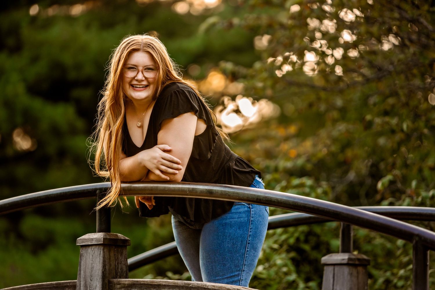 High School Senior girl standing on bridge at Japanese stroll garden at sunset