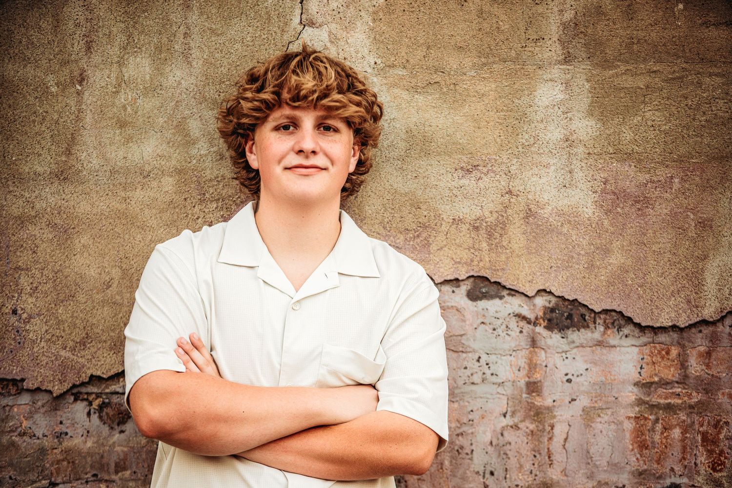 senior boy portrait standing against wall