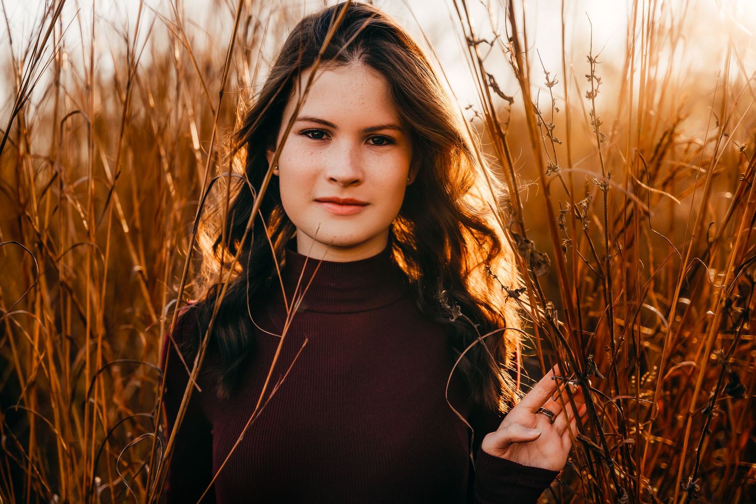 High school senior girl peeking through tall grasses