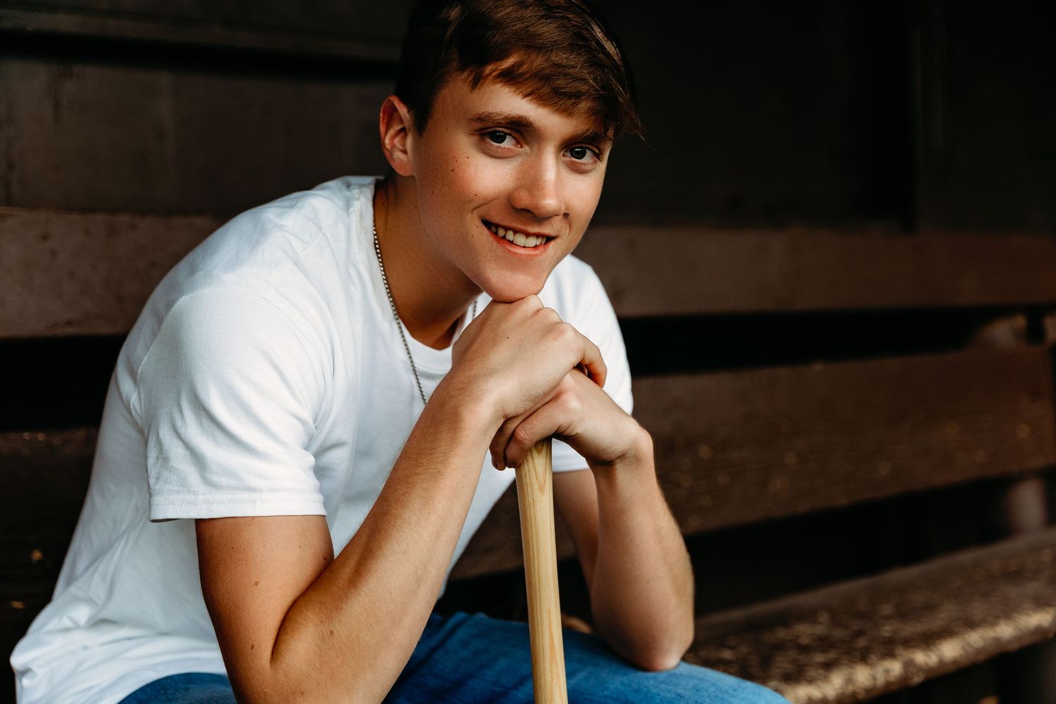 Senior boy portrait in baseball dugout with bat