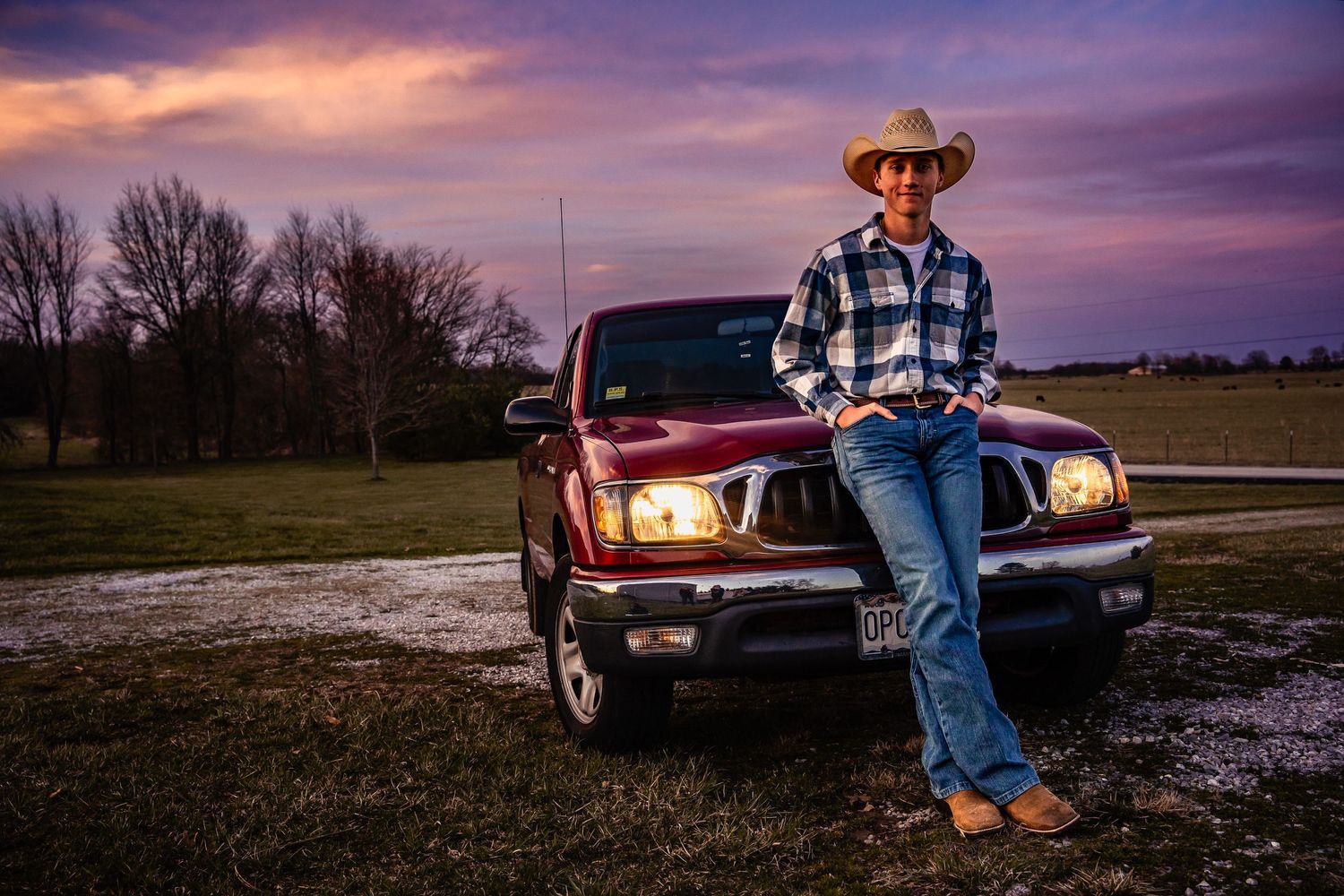 high school senior boy standing in front of truck at blue hour