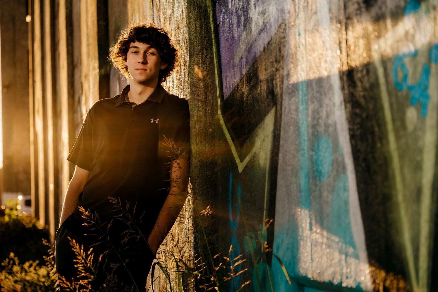 high school senior boy standing next to graffiti wall