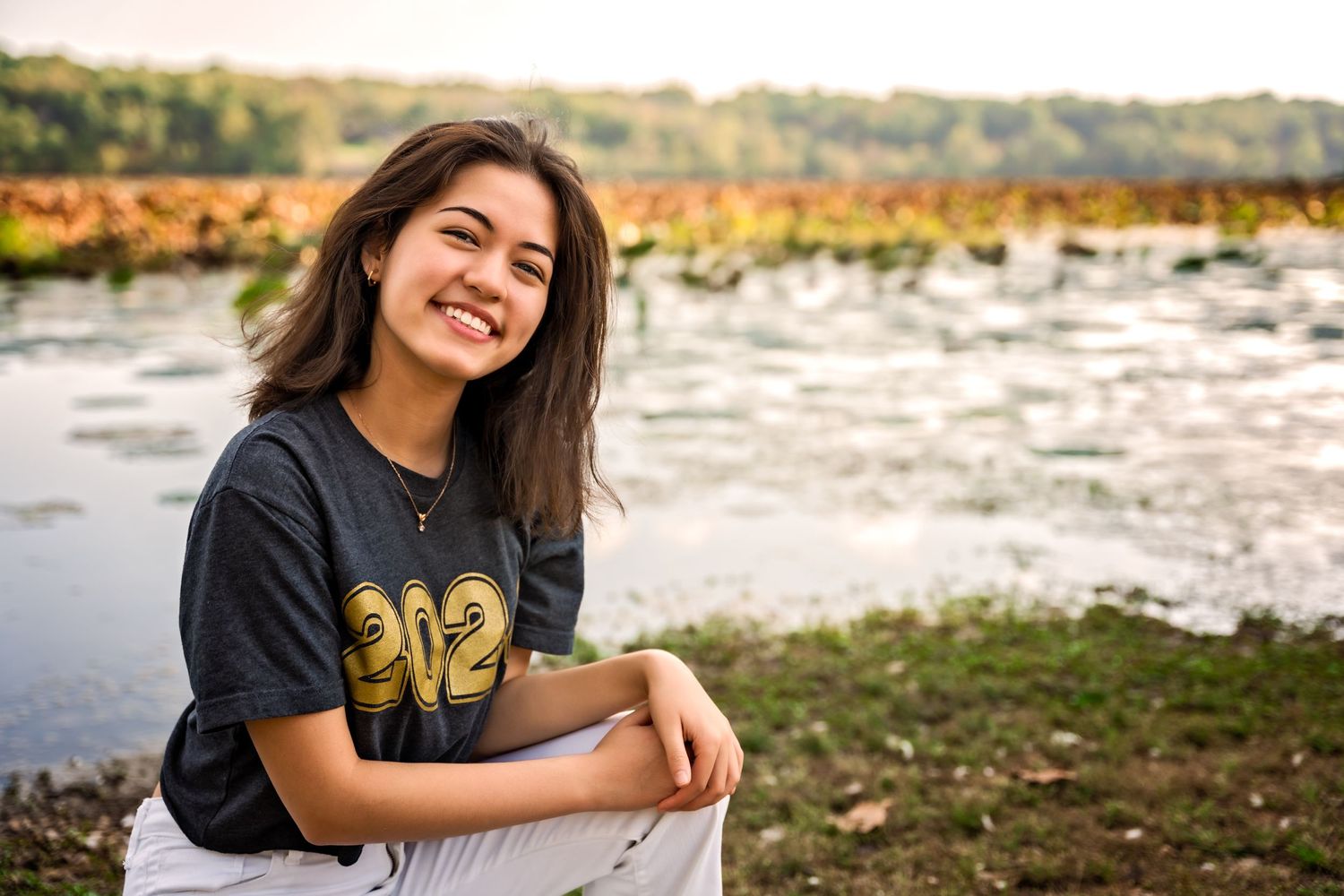 high school senior girl smiling in front of Springfield Lake