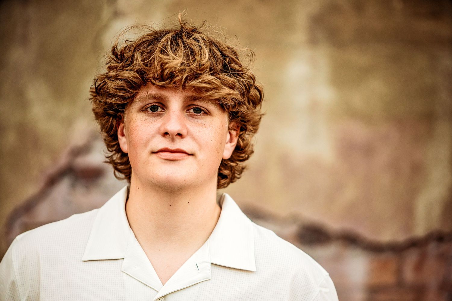 high school senior boy standing in front of wall