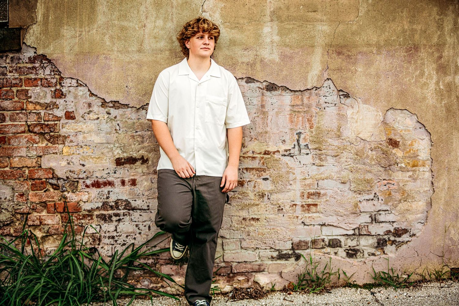 high school senior boy standing in front of wall