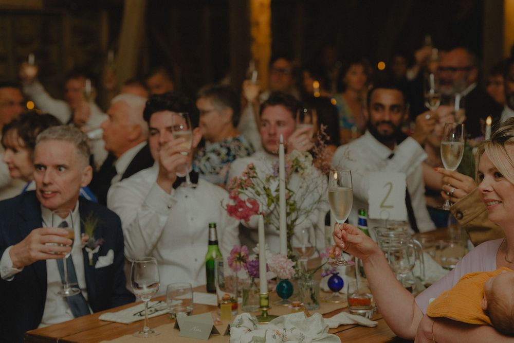 Wedding guests raising champagne glasses in a toast at a elegant reception dinner celebration.