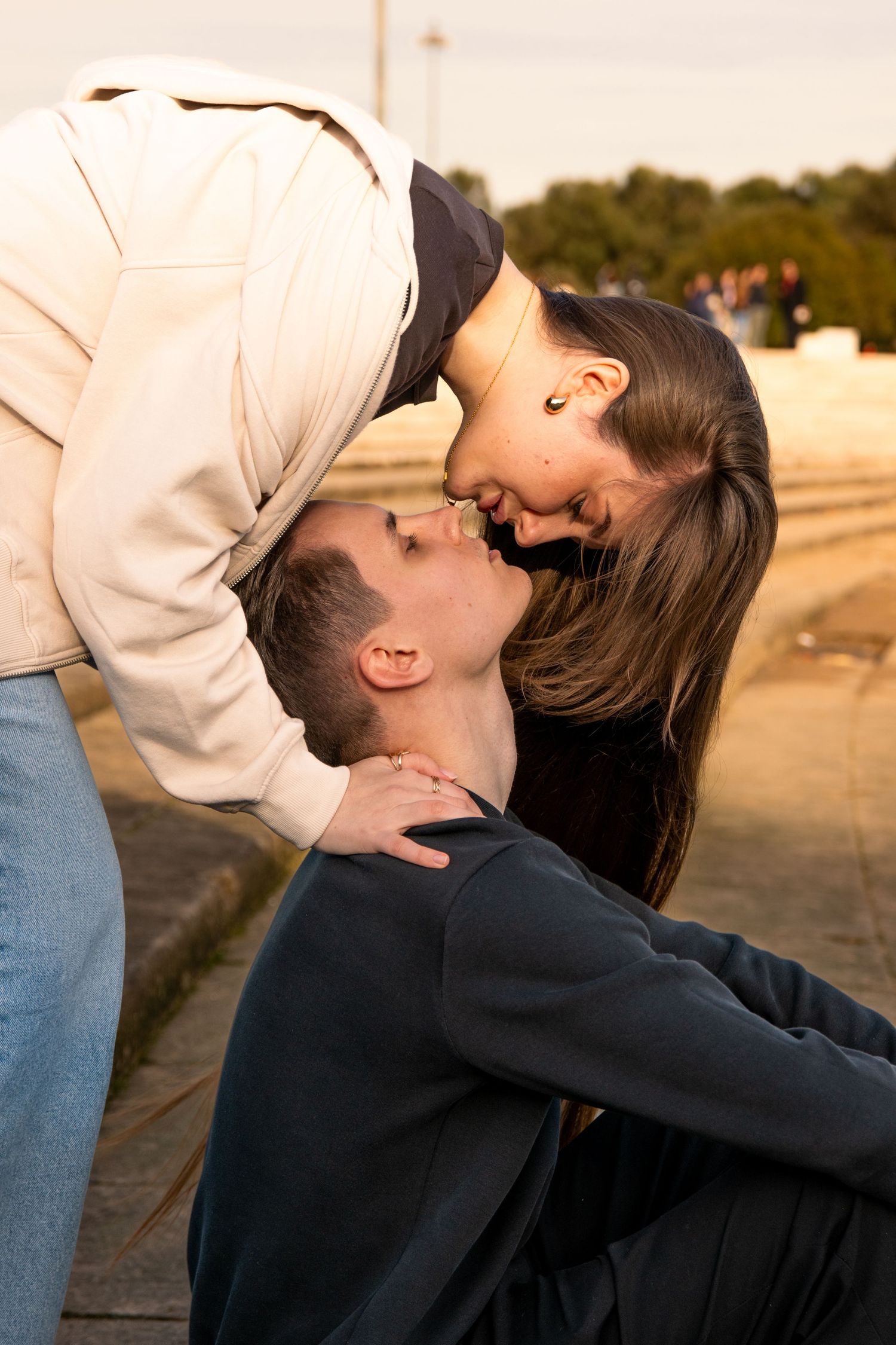 Romantic sunset photoshoot of couple in casual attire embracing outdoors.