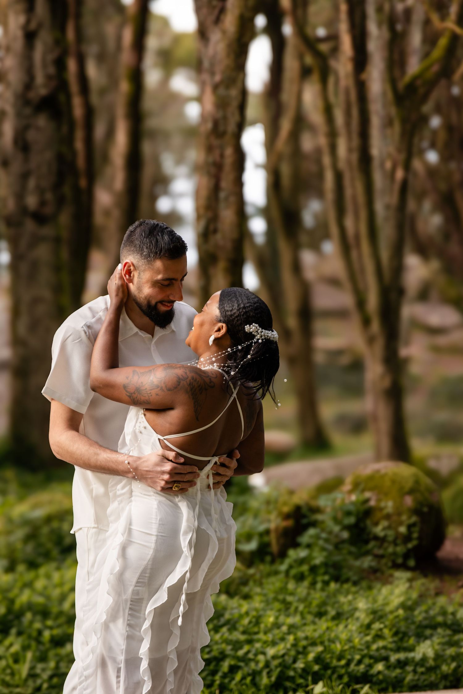 Romantic couple embracing in a sunlit forest setting.