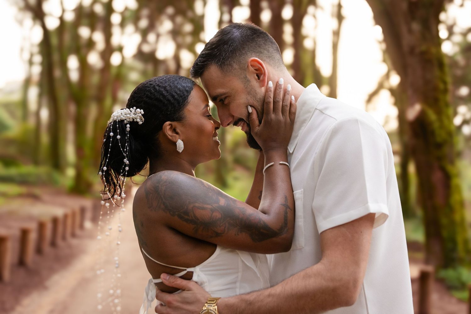 A couple shares an intimate moment on a tree-lined path during sunset.