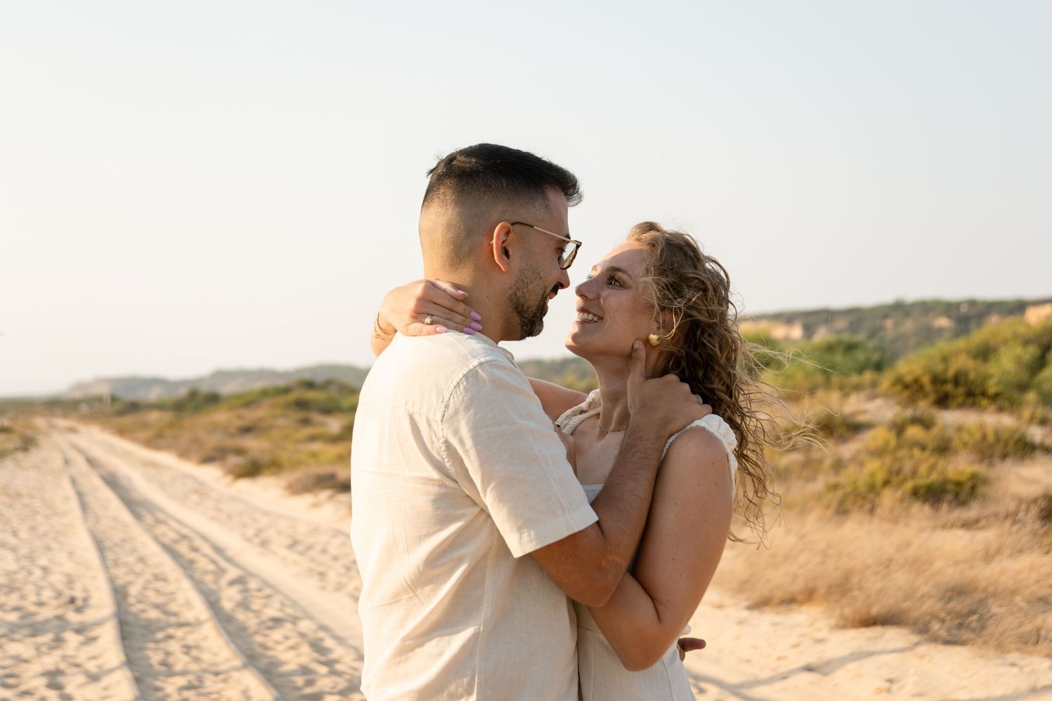 Romantic couple embracing on a sandy beach during golden hour.
