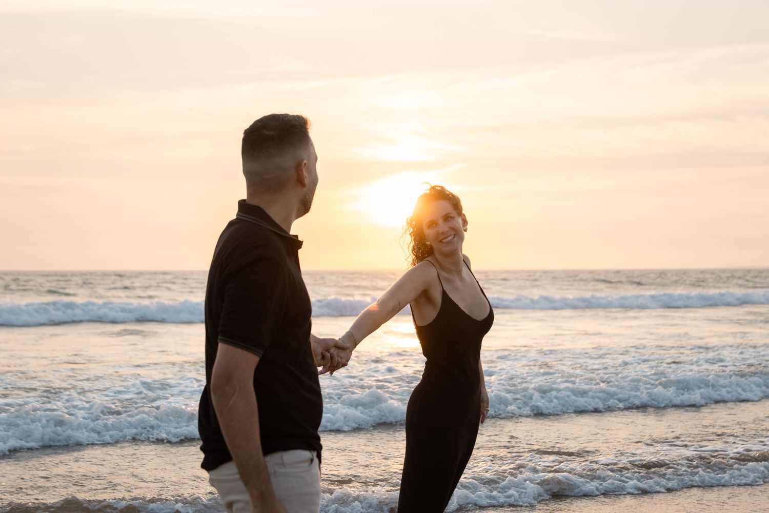 Silhouetted couple sharing an intimate moment against a sunset beach backdrop.