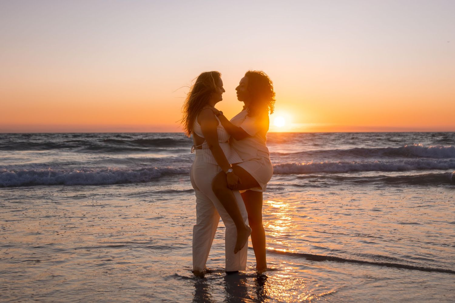 Romantic beach scene at sunset with waves crashing on shore.