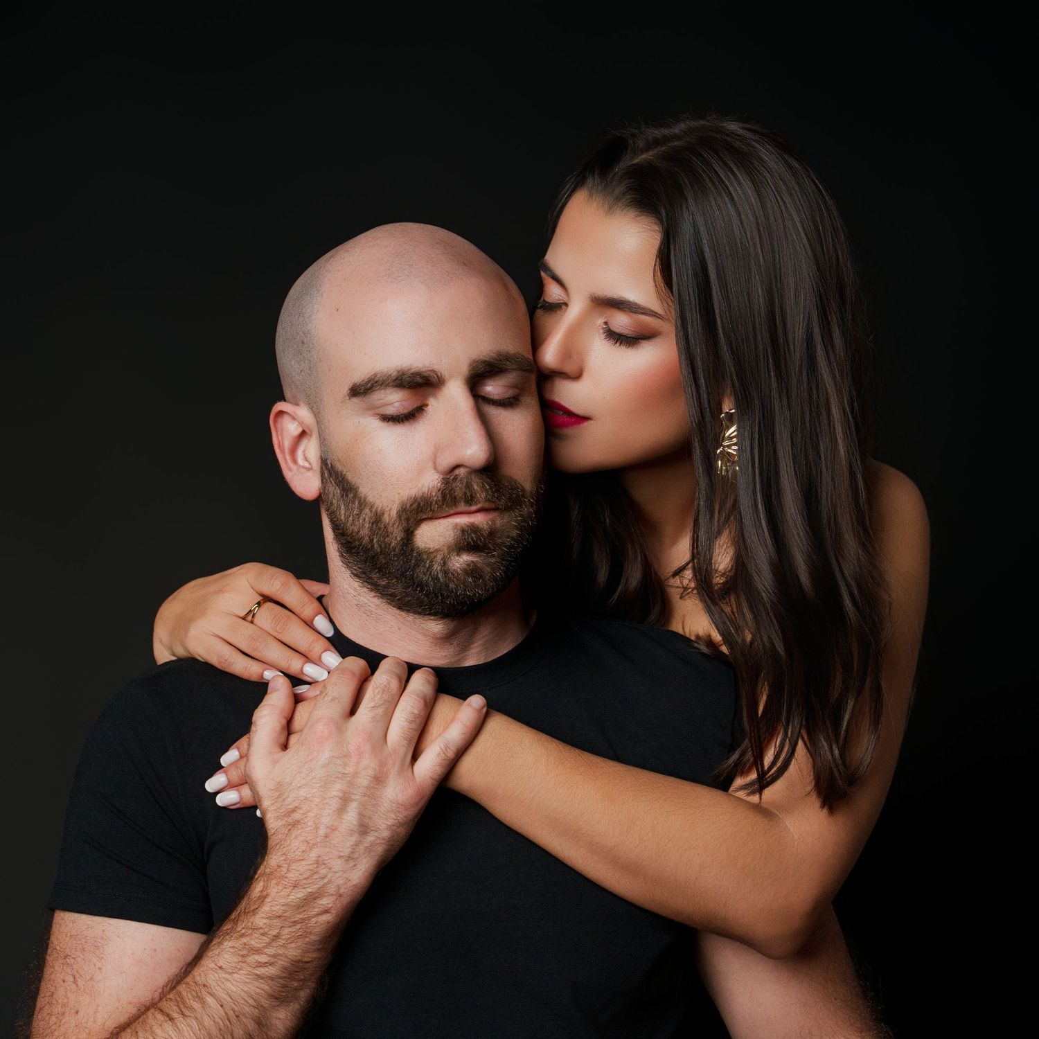 Intimate couples portrait session with dramatic lighting on dark background.