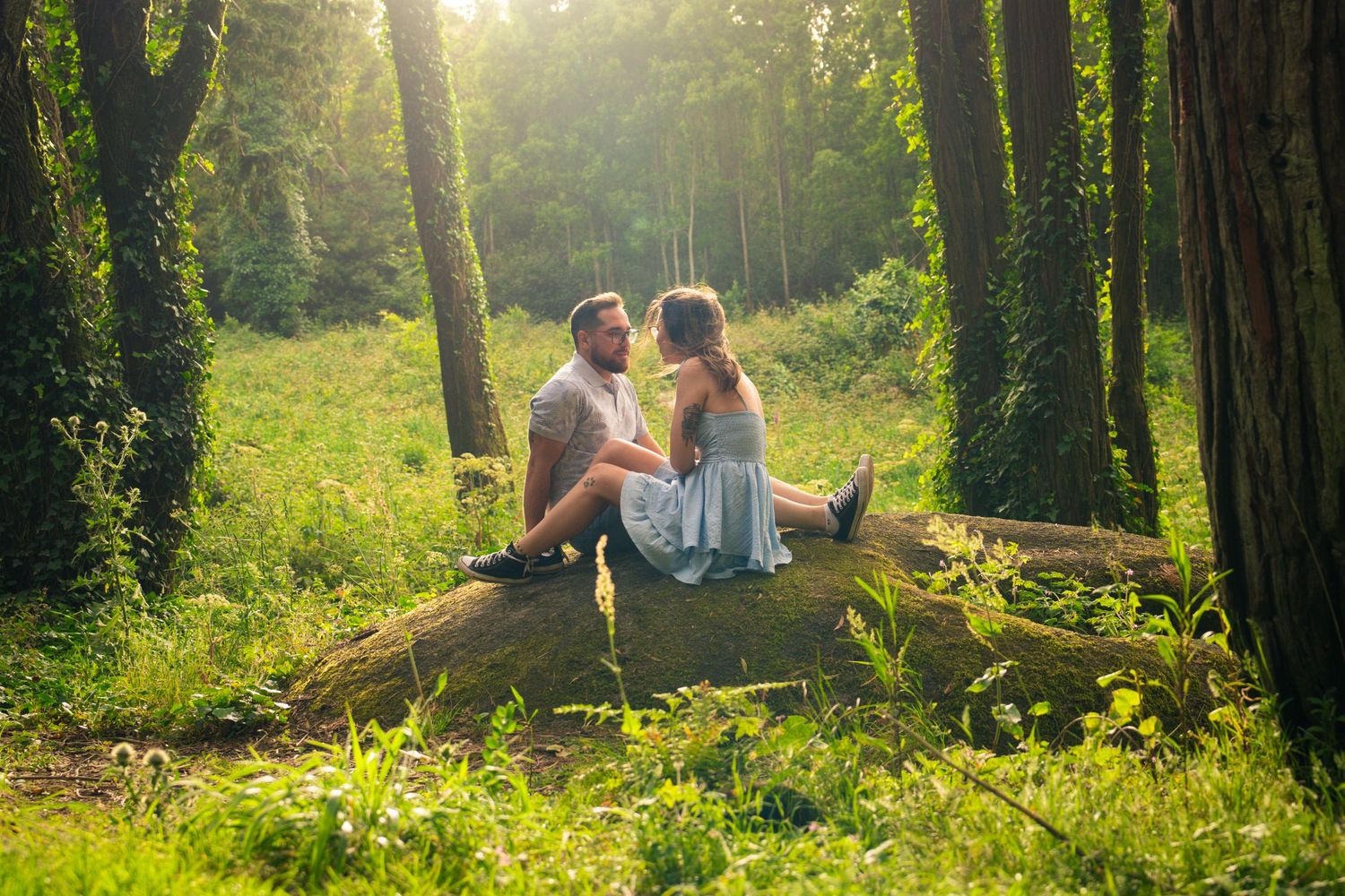 Sunlight streams through trees as a couple relaxes in a peaceful forest setting.