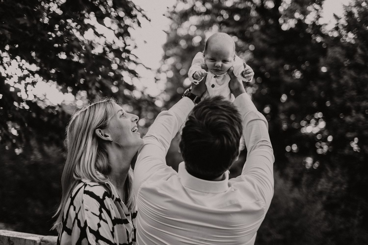 pasgeboren baby wordt lucht in gedragen door zijn ouders in het park in Antwerpen. Ze zijn super blij en gelukkig!