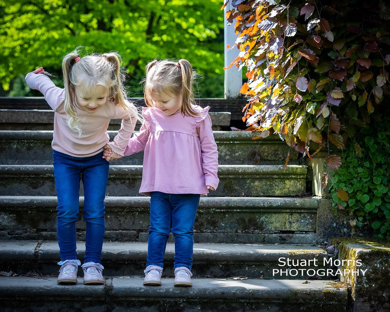 young girl shows her little sister how to jump off a step at Walton hall gardens