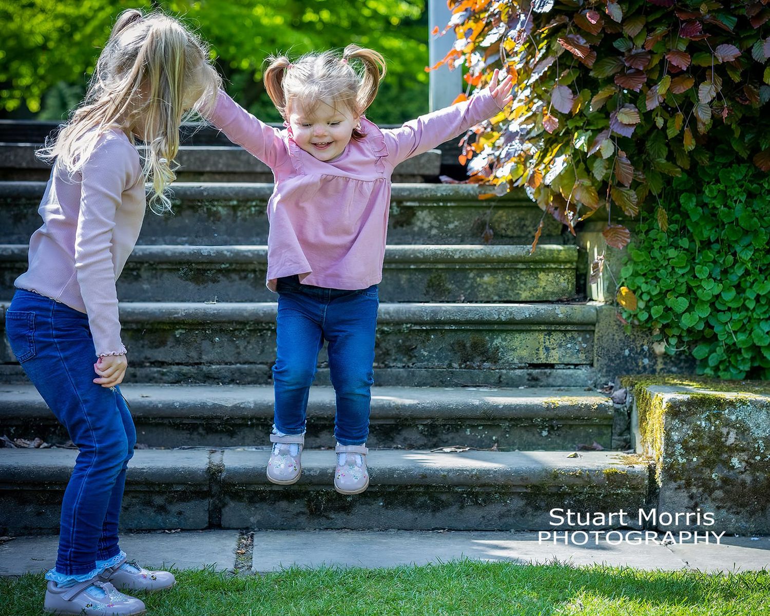 little girl with arms in the air jumps off a step. mini photo portrait outdoor session by Stuart Morris Photography