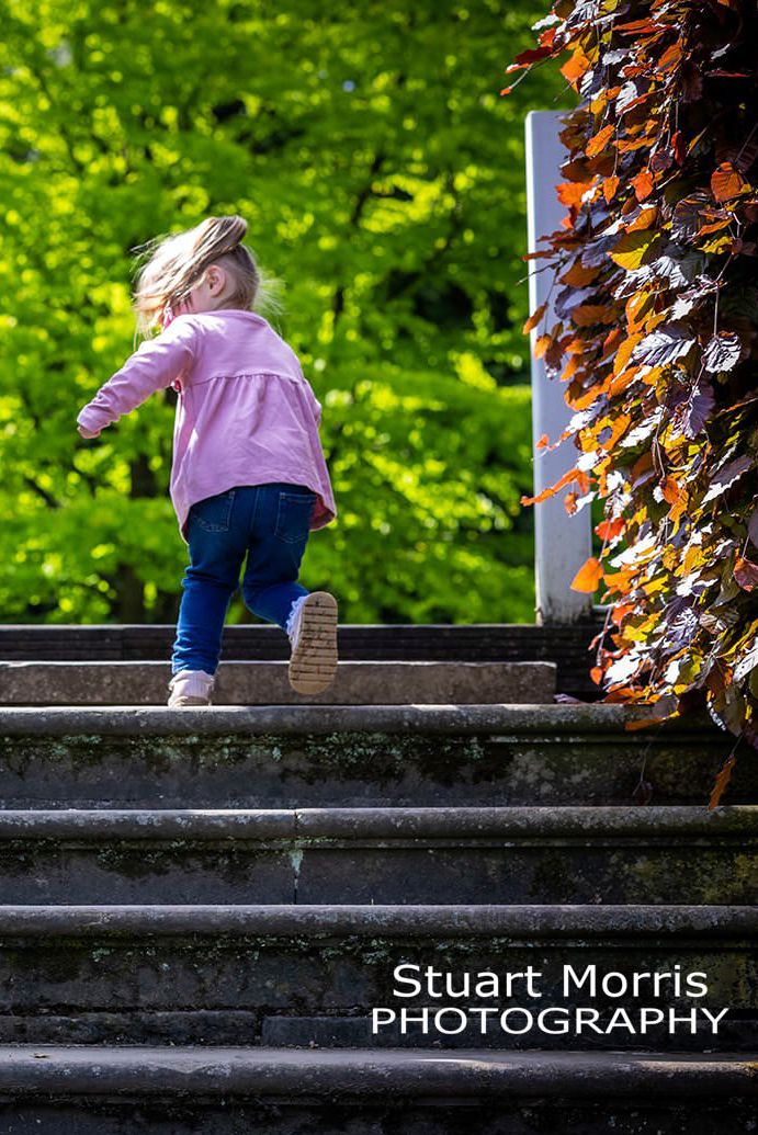 little girl runs up the steps at Walton hall gardens. outdoor portrait session by Stuart Morris Photography