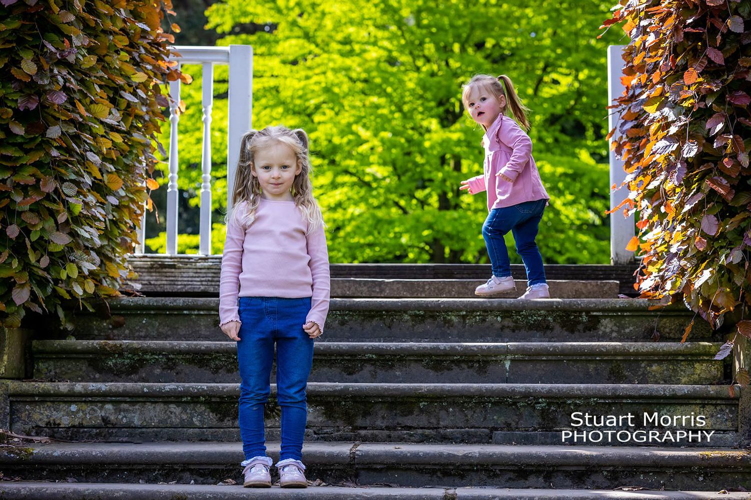 little girl runs up steps and turns to look at her big sister. Walton hall gardens photo session.