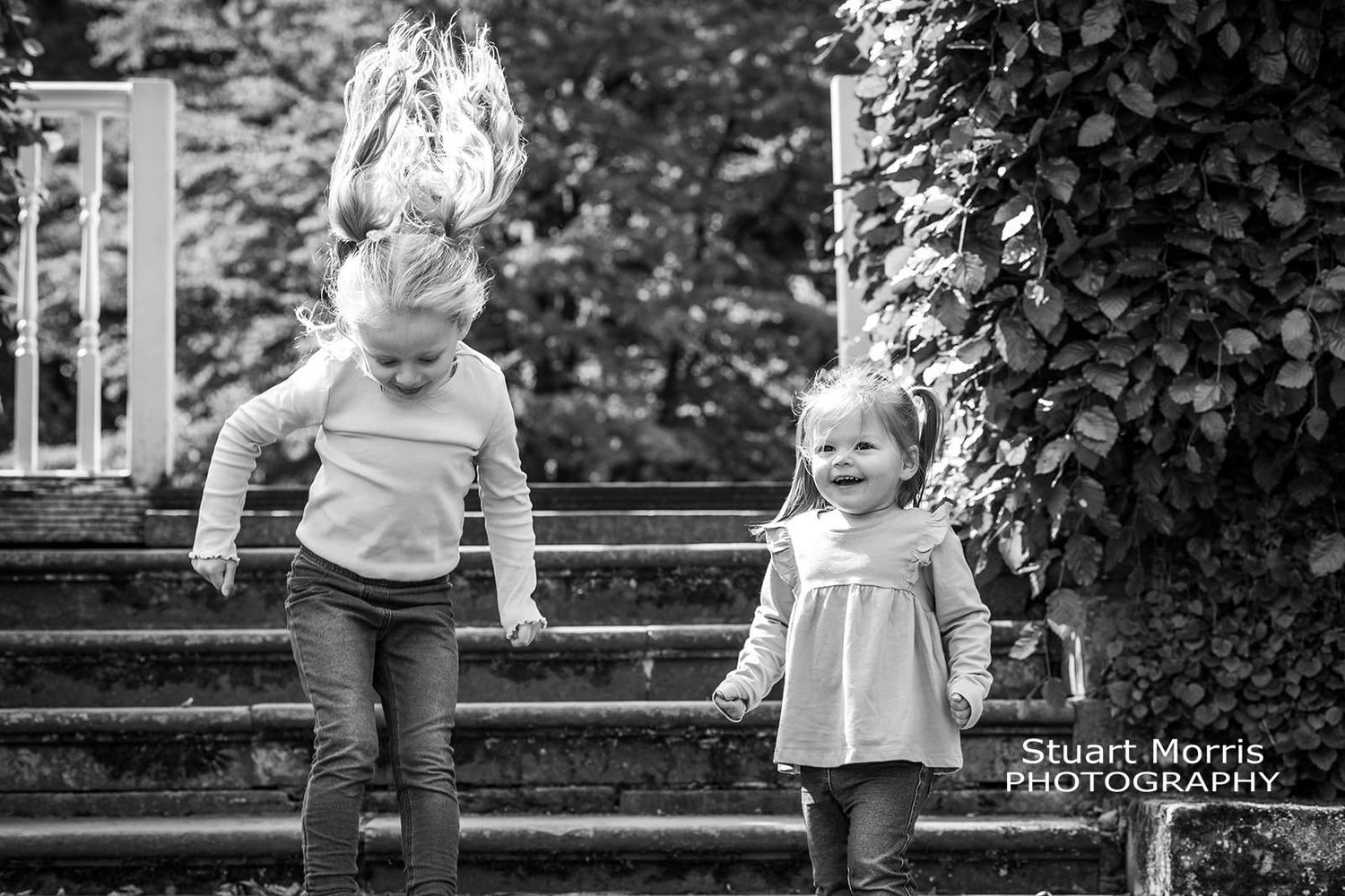 2 little girls jump off the steps at Walton hall gardens in warrington. Stuart Morris Photography.