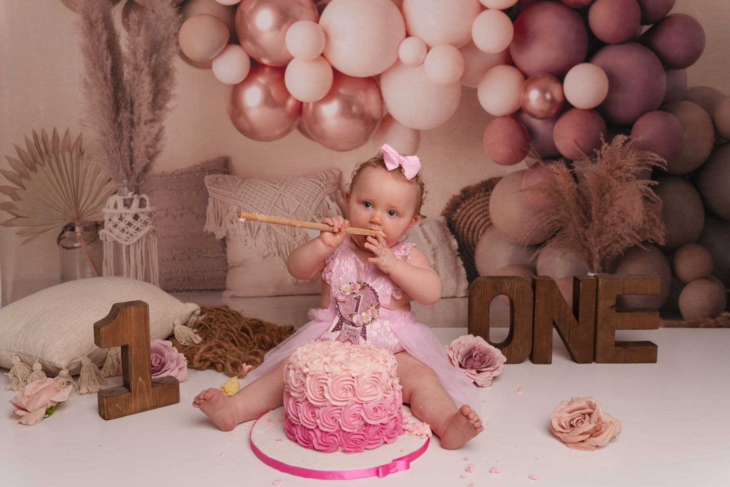Pink ombre cake smash session with balloon arch and boho decorations.