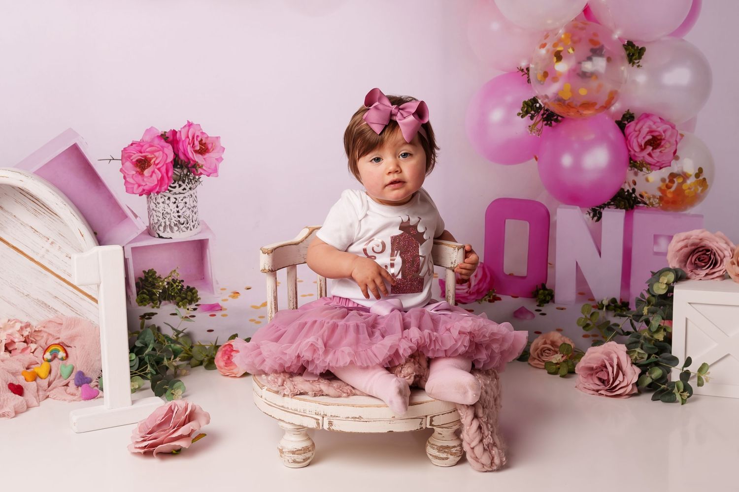 Pink floral first birthday setup with flowers and vintage style decorations.