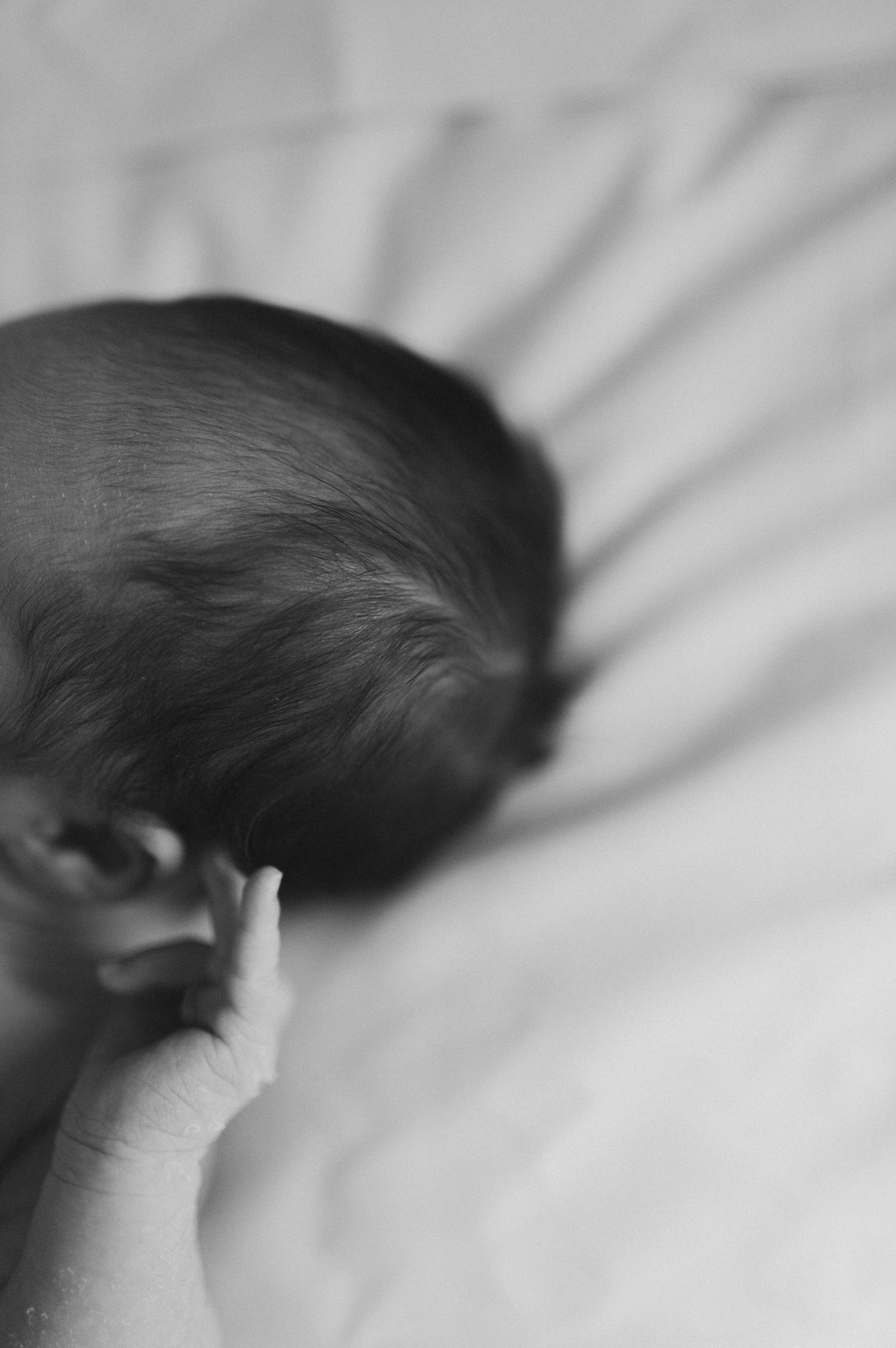 Black and white close-up image of a baby's head with shadows casting patterns.