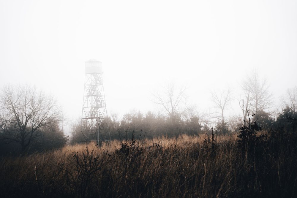 Rolling hills with transmission towers visible through morning haze creating an industrial landscape.