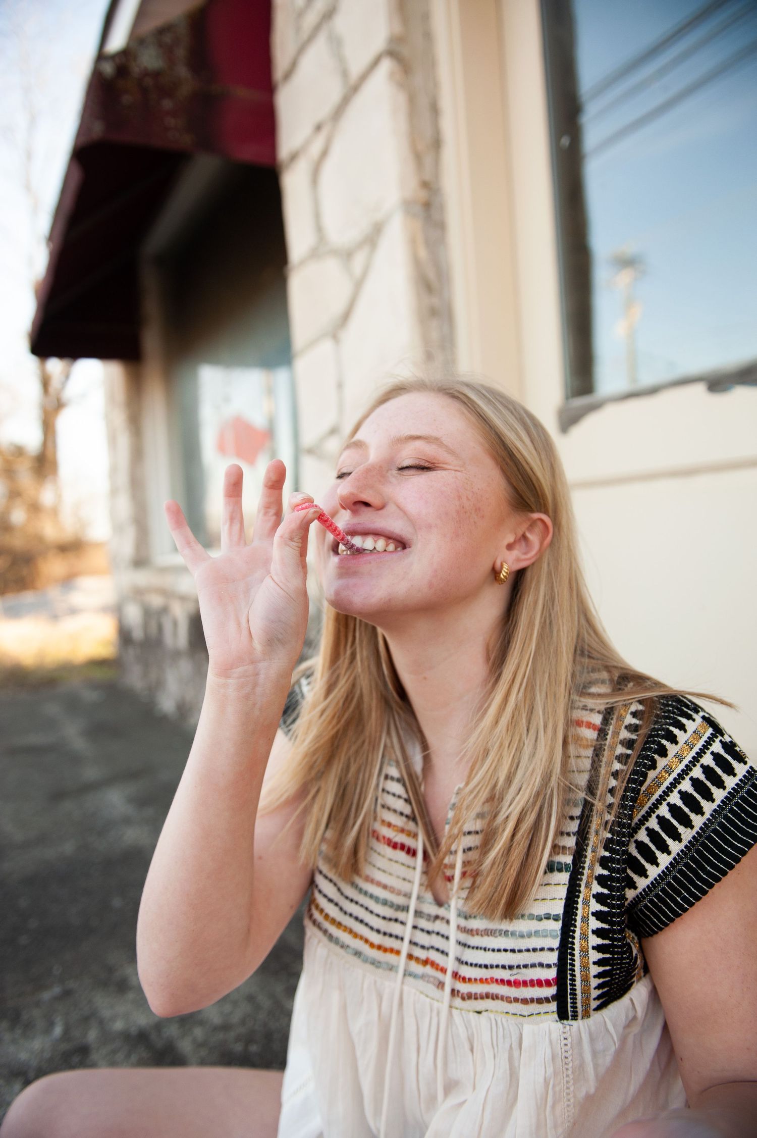 Carefree moment captured outside with genuine laughter and expressive hand gesture.