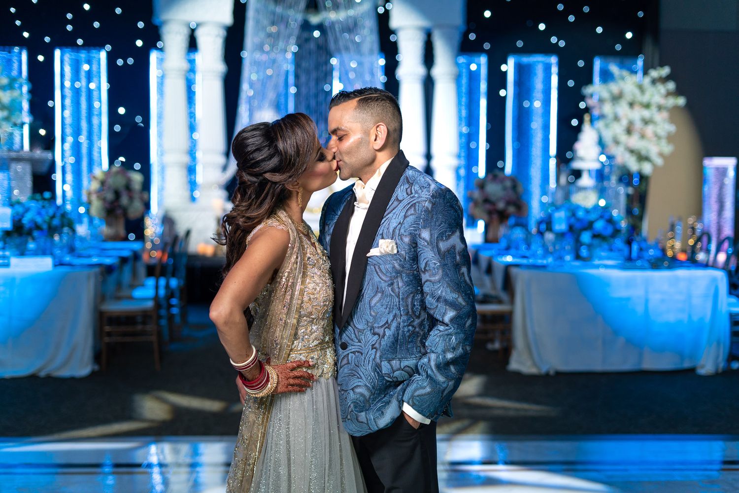 Couple sharing a romantic kiss on the dance floor at an elegant blue-themed Indian wedding reception at Paramount Event Center in Toronto.