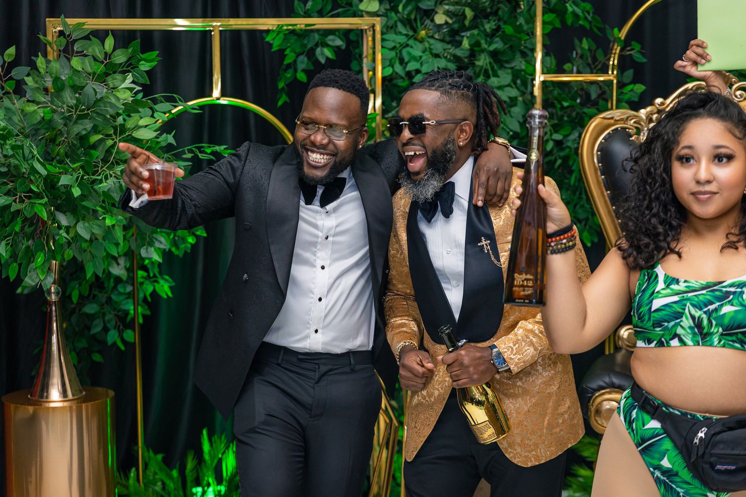 Three well-dressed individuals pose enthusiastically at a formal event.