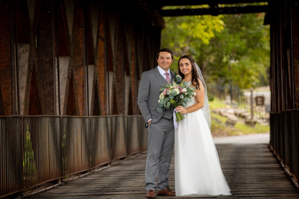 a bride and groom pose on a covered bridge at Big Cedar Lodge in Branson, Missouri