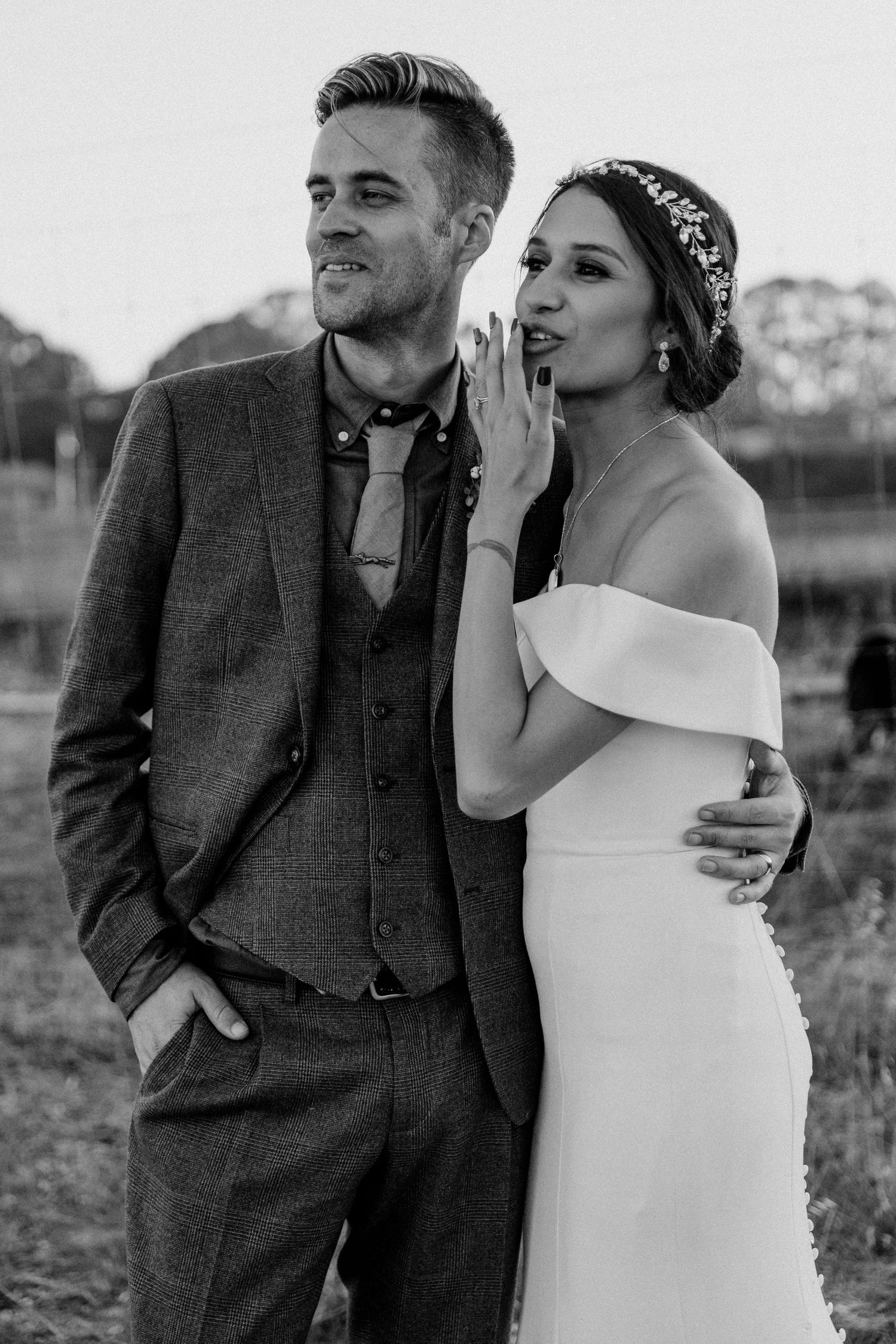Wedding couple in elegant attire poses together in black and white photography.