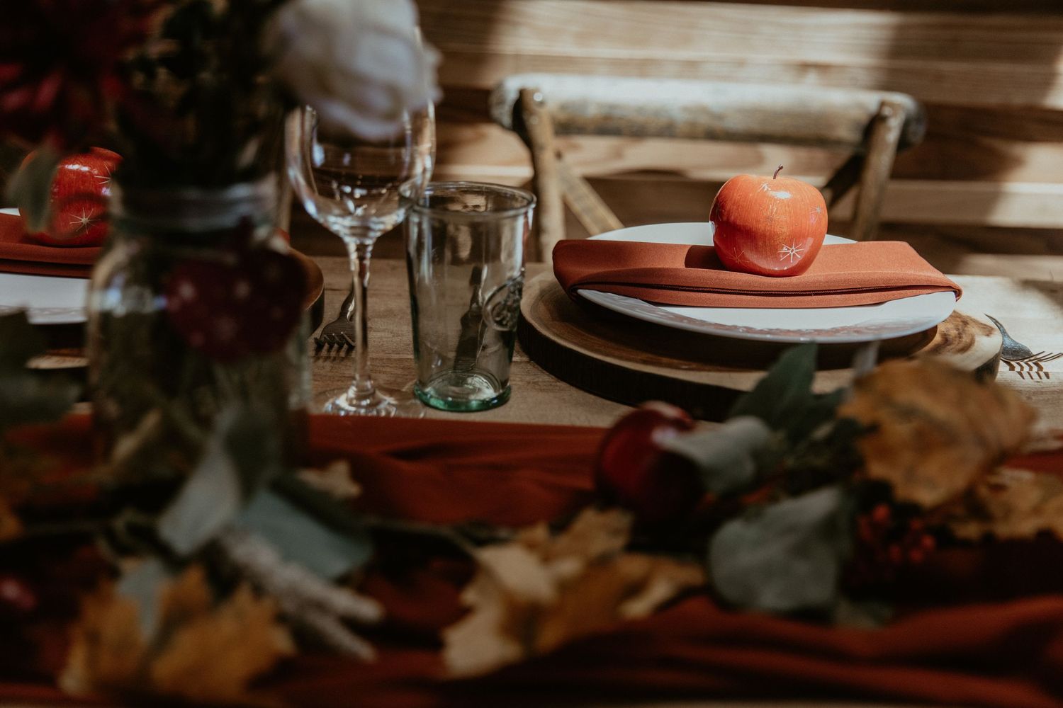Rustic wedding table setting with terracotta details and wine glasses.