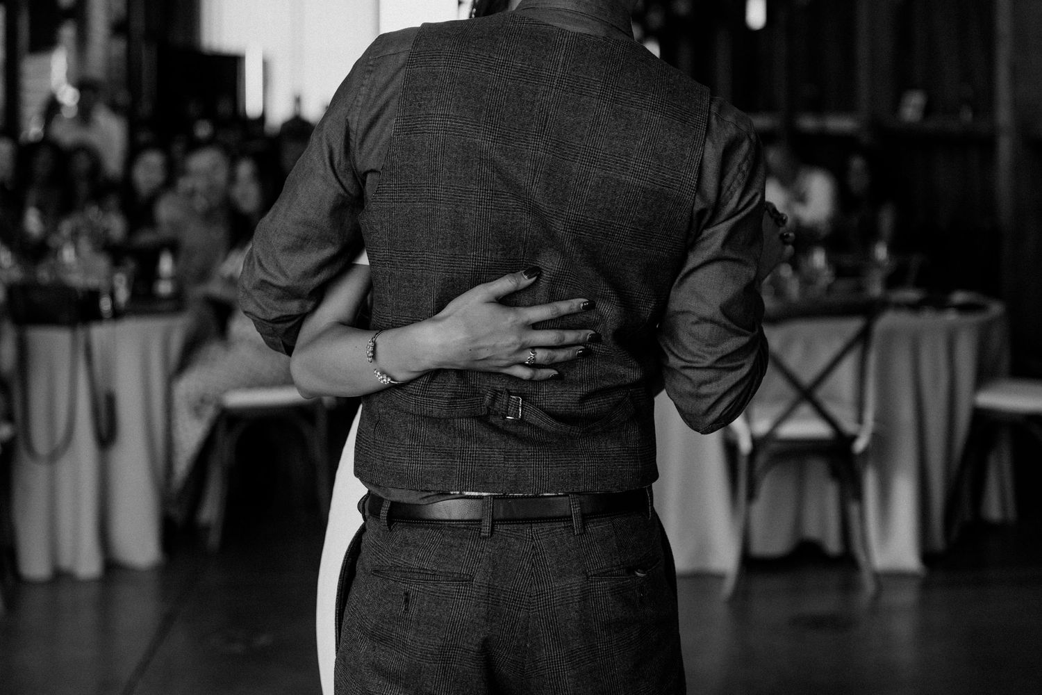 Black and white photo of dancing couple during wedding reception in barn venue.