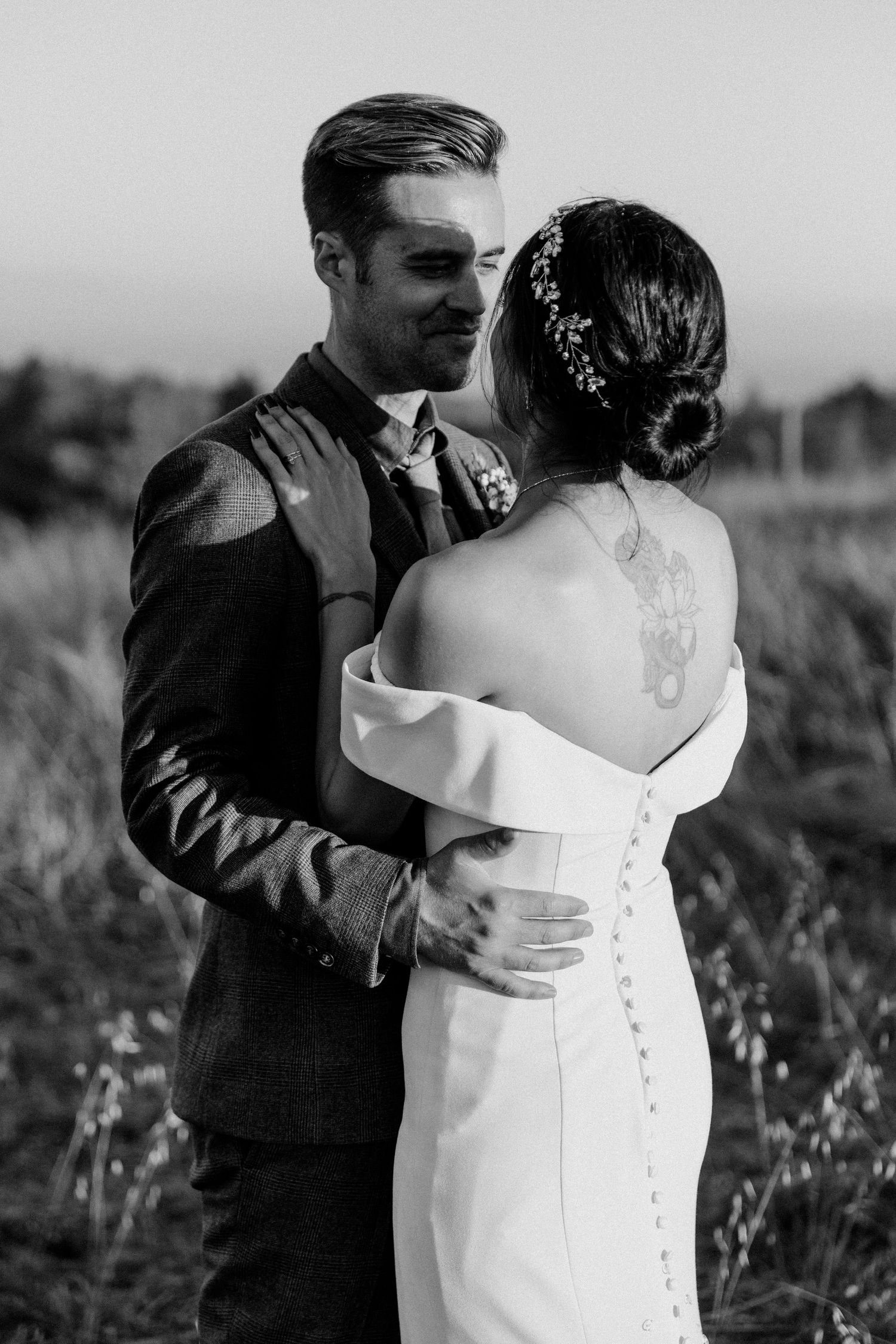 Black and white portrait of wedding couple showing detailed back of bride's dress.