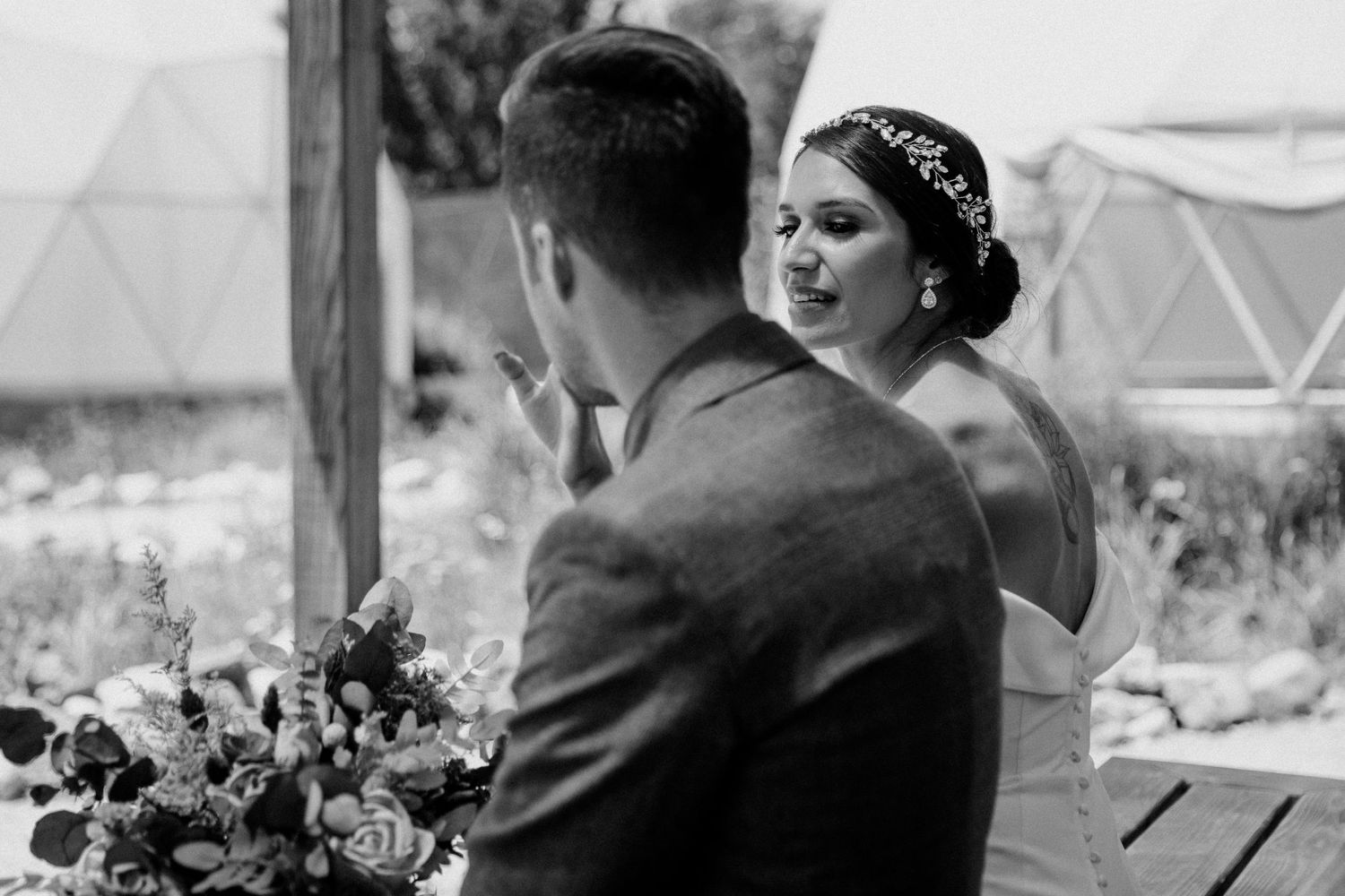 Black and white photo of a couple having an intimate moment at their outdoor wedding.